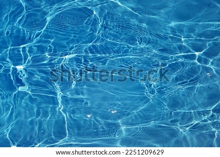 Defocus blurred transparent blue colored clear calm water surface texture with splashes and bubbles. Trendy abstract nature background. Water waves in sunlight with caustics. Blue water shinning  Royalty-Free Stock Photo #2251209629