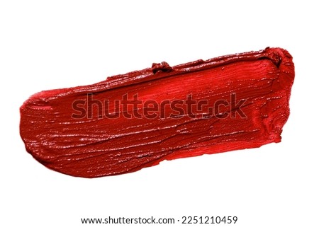 Red lipstick smear smudge swatch isolated on white background. Cream makeup texture. Bright color cosmetic product brush stroke swipe sample
