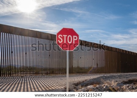 US - Mexican border wall with stop sign in foreground - Arizona