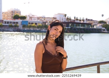 young and beautiful woman from south america and dressed in short dress is on vacation in seville. In the background the river. The woman smiles and makes different expressions. Travel and vacation. Royalty-Free Stock Photo #2251269439