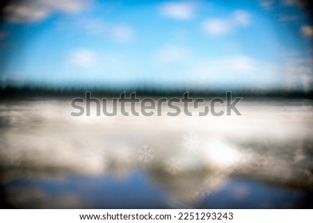 Abstract photo of a blurred river with a blue sky and white clouds with snow on the banks. With clear snowflakes.