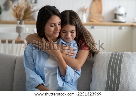 Cute girl daughter embracing mother from behind, expressing gratitude, kid telling mom she loves her. European family mommy and child cuddling, enjoying time together at home. Mother-daughter bond Royalty-Free Stock Photo #2251323969