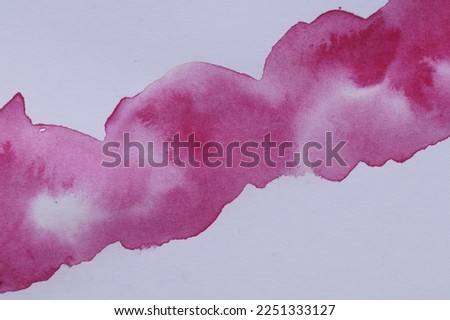 Blot of pink watercolor paint on white paper, top view
