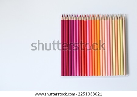 A palette of colored pencils of yellow and red shades lying on a white background.