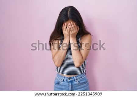 Young teenager girl wearing casual striped t shirt with sad expression covering face with hands while crying. depression concept.  Royalty-Free Stock Photo #2251345909