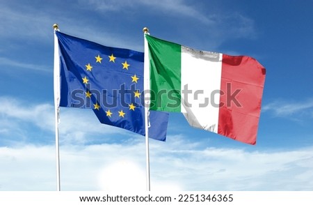 Italian flag and EU flag on cloudy sky. waving in the sky