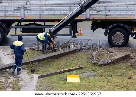 Utility workers remove a fallen electric pole after a car accident using a crane. Royalty-Free Stock Photo #2251356957