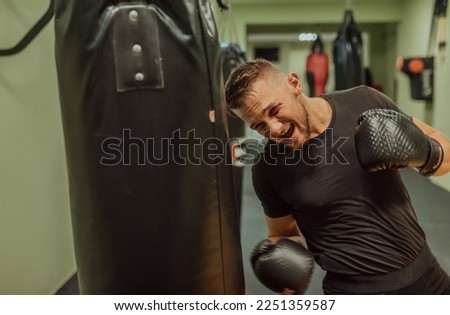 A young sporty man exercise intensively while punching boxing bag in a gym. Royalty-Free Stock Photo #2251359587
