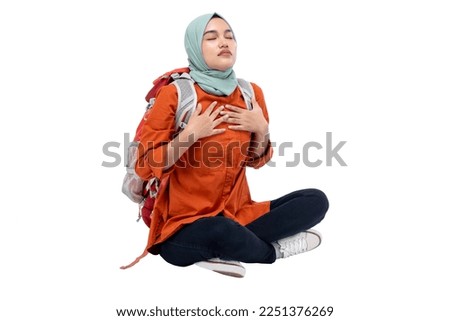 Asian Muslim woman in a headscarf sitting with a backpack feeling chest pain isolated over white background