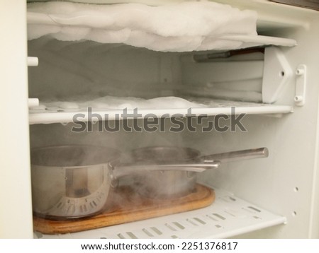 Defrosting the refrigerator freezer with hot water pots Royalty-Free Stock Photo #2251376817