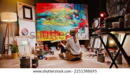 Back view of talented concentrated Caucasian woman professional artist sitting on floor in studio in evening painting drawing on big canvas, creativity work, contemporary creative painter Royalty-Free Stock Photo #2251388695