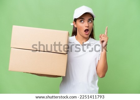 Delivery caucasian woman holding boxes isolated on green chroma background thinking an idea pointing the finger up