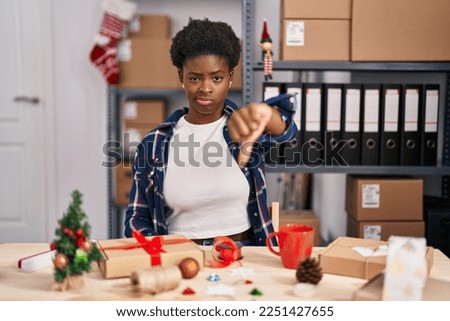 African american woman working at small business doing christmas decoration looking unhappy and angry showing rejection and negative with thumbs down gesture. bad expression. 