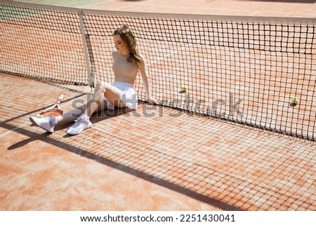 beautiful young woman relaxing sitting on tennis court in summer