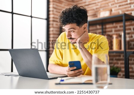 Young caucasian man using laptop and smartphone at home