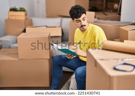 Young caucasian man writing on notebook sitting on sofa at new home