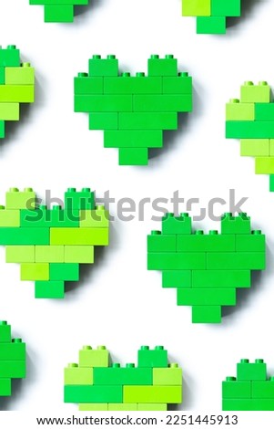 Green hearts from blocks isolated on white background, minimal geometric pattern from plastic blocks, shapes heart from child construction. Top view repeat pattern, Toys and games.