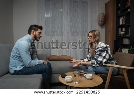 Young married couple husband and wife sitting at home having problems in their marriage and a cold relationship. A boyfriend and a girlfriend have an argument about spending too much money. Royalty-Free Stock Photo #2251450825