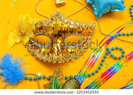 Carnival mask with beads and confetti on yellow background