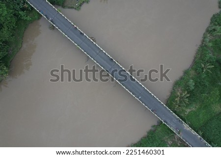 Aerial view of the long bridge over the brown watery river. the river delta is overgrown with green weeds. jembatan kali Progo. 