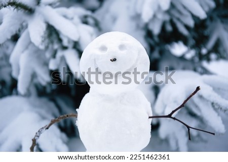 Smiling snowman. Makingsnowman in the forest from the first snow. Snowy winter, coniferous trees covered with snow. Portrait of snowman. Royalty-Free Stock Photo #2251462361