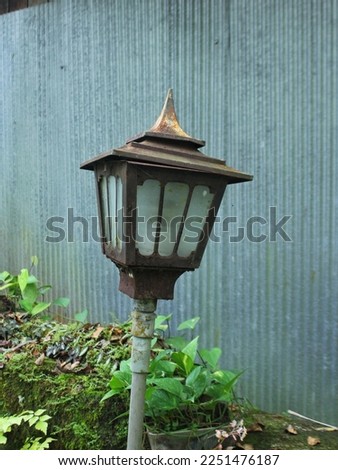 In the past, decorative lamps were installed in the garden of the house, with a zinc wall behind it.