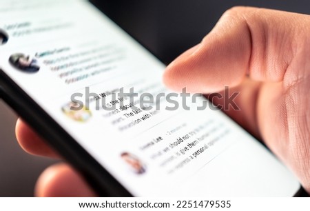 News feed in social media, post message, comment and profile page in mobile phone. Online conversation in digital community network blog. Swipe smartphone screen with finger. Holding cellphone in hand Royalty-Free Stock Photo #2251479535