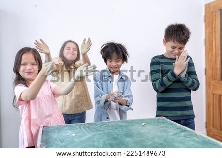 Children in class room happy laughing enjoy chalk drawing on green board showing dusty dirty hand