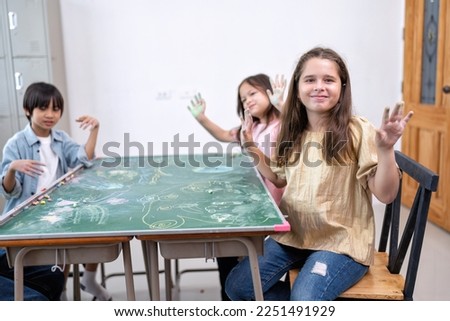 Children in class room happy laughing enjoy draw picture on green board