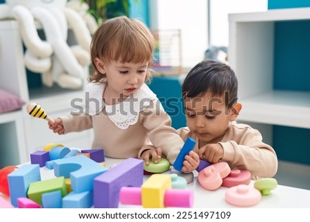 Two kids playing with construction blocks standing at kindergarten