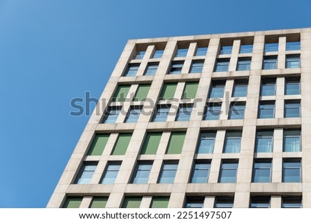 Multistorey building standing against blue sky background. Bottom view of modern skyscrapers in business district. Geometry modern of office buildinges. Window storey exterior close up. Royalty-Free Stock Photo #2251497507