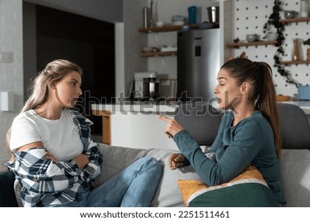 Two young women friends roommates business partners and owners of a small business are arguing at home due to the inappropriate spending of money and increased expenses on household bills. Royalty-Free Stock Photo #2251511461