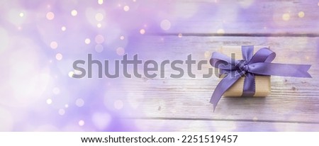 Gift box with purple bow and bokeh lights with hearts - Happy Birthday, Mother's Day or Wedding card with copy space and background banner