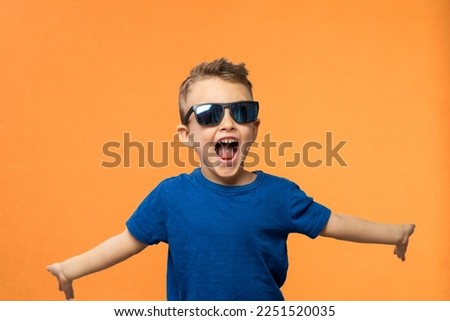 Portrait of surprised cute little toddler boy in sunglasses. Child with open mouth having fun isolated over orange background. Looking at camera. Wow funny face Royalty-Free Stock Photo #2251520035