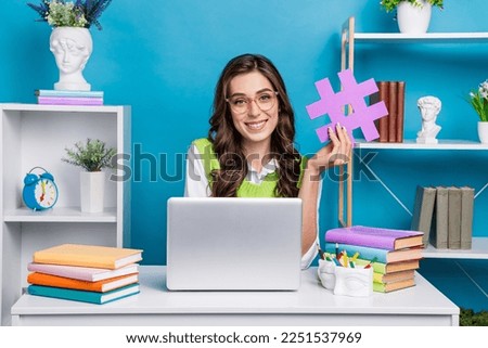 Photo portrait of pretty young girl eyeglasses hold hashtag icon workstation wear trendy green garment isolated on blue color background Royalty-Free Stock Photo #2251537969