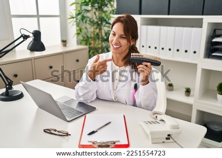 Young latin woman wearing dentist uniform holding whitening test at clinic