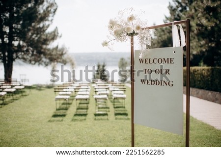 wedding reception board on the background of the decorated ceremony, empty rows of chairs, preparation for the wedding ceremony, waiting for guests