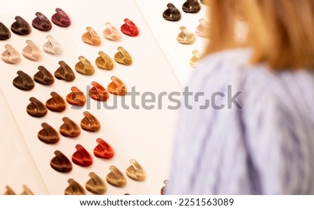 Hairdresser salon Woman chooses, looks at hair color samples on palette swatch book in stylist office or home. Beautician,dyeing,changing hair colour,natural,non-toxic,safe haircare concept Horizontal