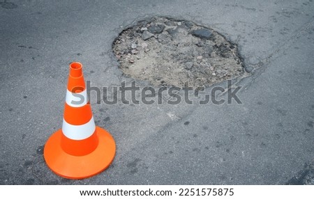 Holes in the road.Asphalt repair. An orange cone indicates damage to the roadway,