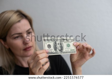 Checking counterfeit money light. 100 dollars against the window in his hand. Check for watermark on new hundred dollar bill. translucence of the American currency.