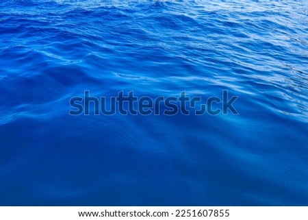 Very nice sea water background or backdrop with selective focus. Small waves of natural water surface texture. Still calm ripples colorful blue wave in a river or ocean. Royalty-Free Stock Photo #2251607855