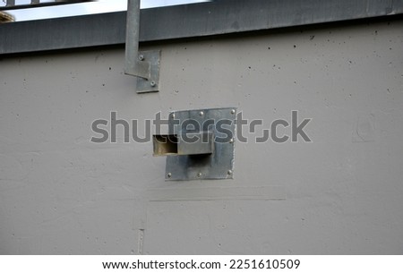 a bridge railing with vertical fence posts anchored into the ground with four concrete screws. the railing is fixed from the side of the bridge into the concrete. gutter, tube, pipe, sewage treatment