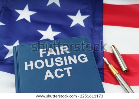 Law concept. On the US flag lies a pen and a book with the inscription - FAIR HOUSING ACT