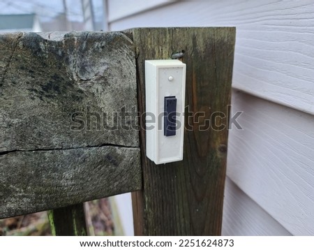 A door bell for a house on a wooden beam next to a railing instead of the house.