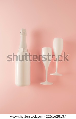 Two white champagne glasses and a white champagne bottle on a pink background, the concept of celebration, Valentine's day, birthday