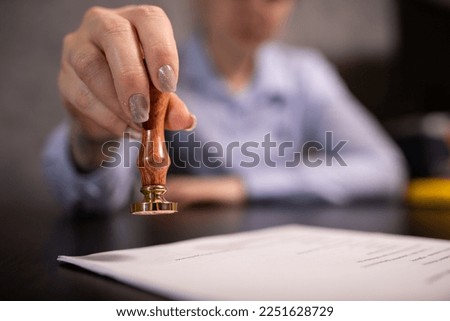 A lawyer in a purple shirt certifies a document on a black table