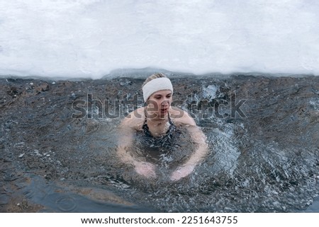 young caucasian girl swimming in cold water in winter, healthy lifestyle, tempering concept Royalty-Free Stock Photo #2251643755