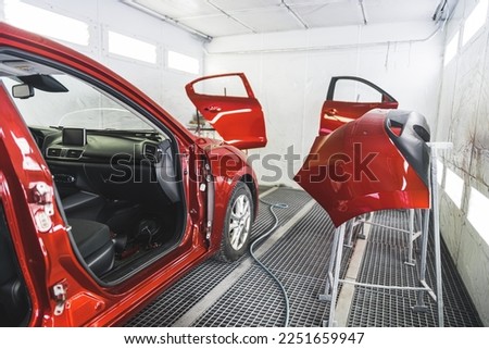 A luxury red car in a paint shop with its doors removed for a fresh coat of paint. High-quality photo Royalty-Free Stock Photo #2251659947