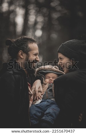 New born family photo shoot in the fall by the woods with happy parents smiling at each other