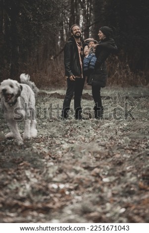 New born family photo shoot in the fall by the woods with dog running to chase a squirrel